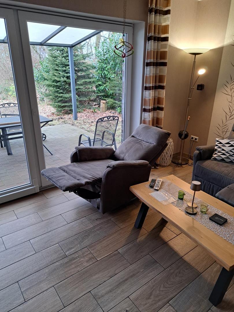 Loungebereich mit Sessel, Couch und Terrasse mit Gartenblick.