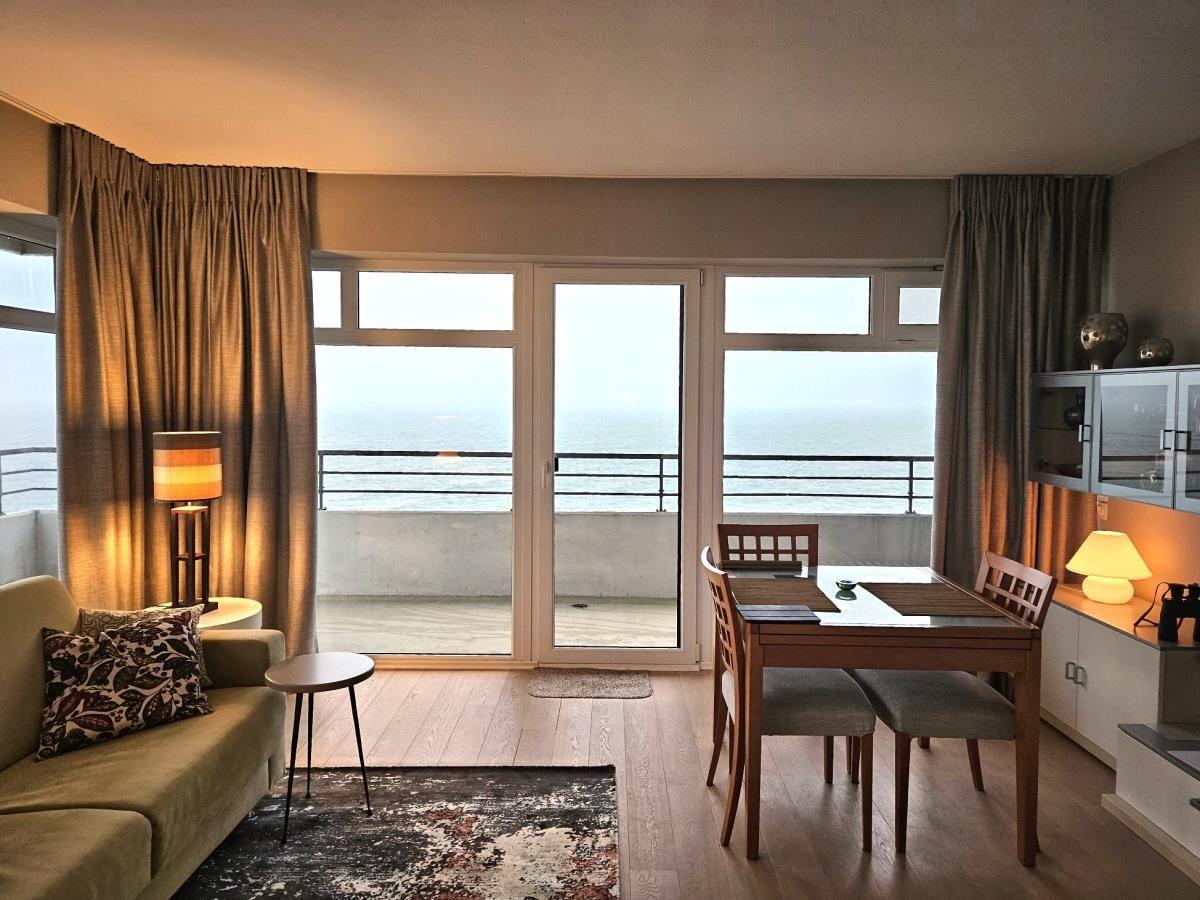 Wohn- und Essbereich mit Blick auf das Meer durch Glastüren.