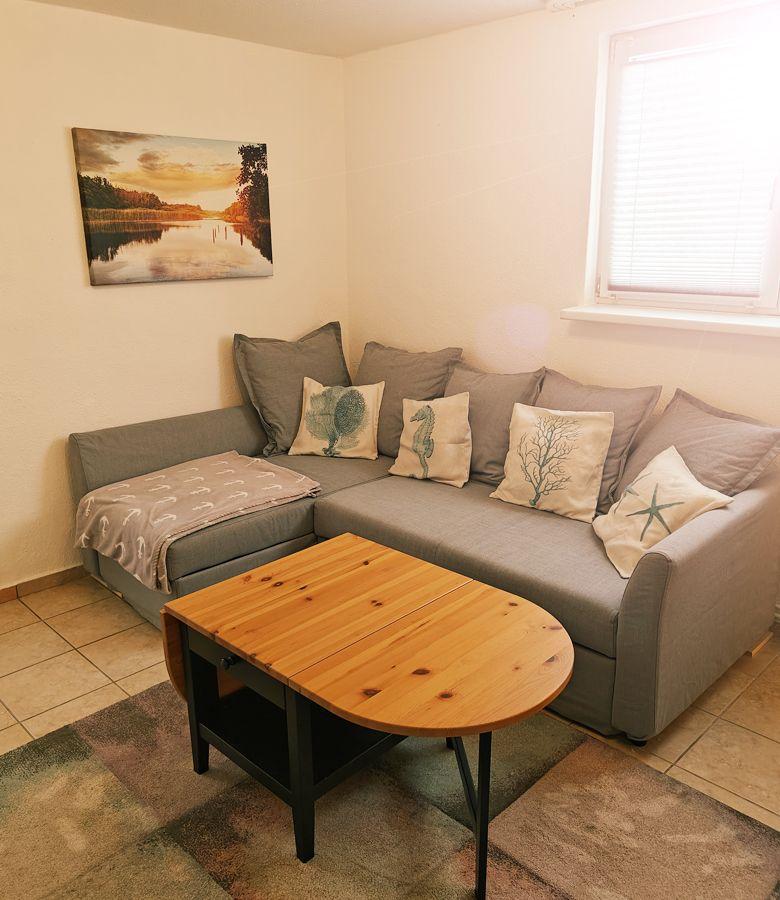 Wohnzimmer mit Ecksofa, Holztisch und Wandbild an der Wand.