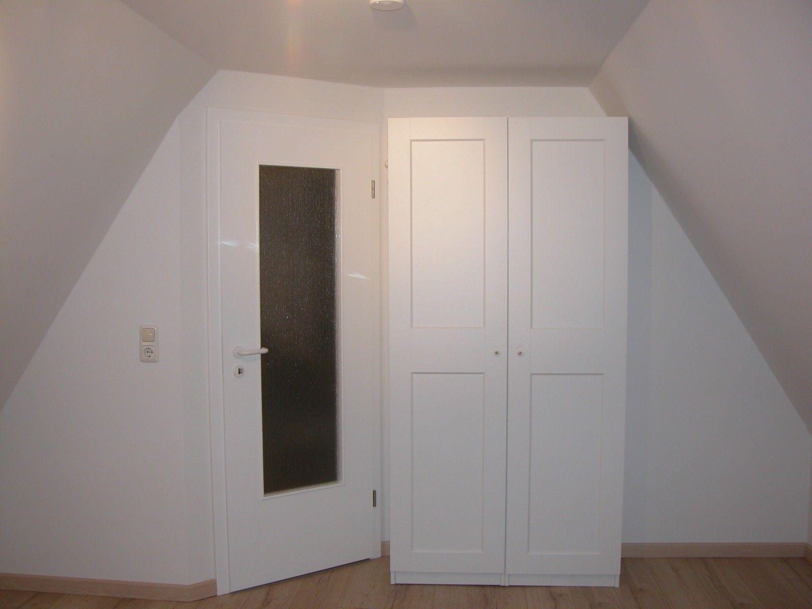 Zimmer mit weißen Türen und schrägen Wänden, Holzboden und Steckdose.