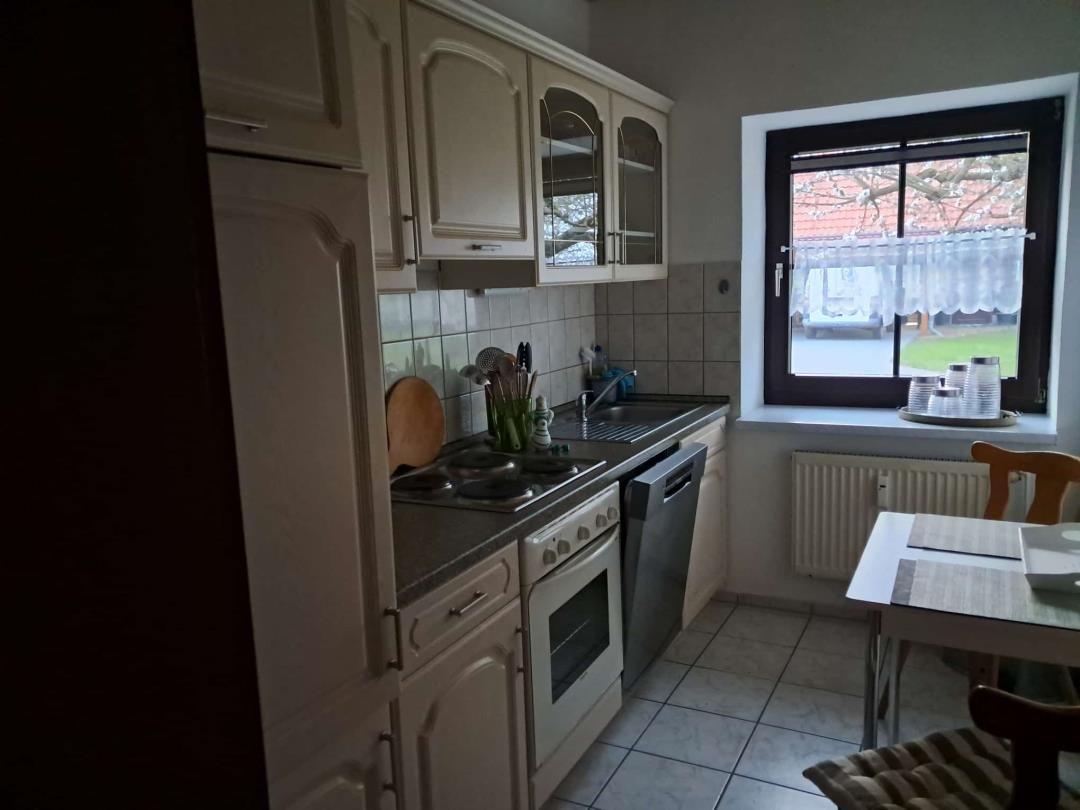 Küche mit Arbeitsplatte, Spüle, Herd und Fenster mit Blick nach draußen.