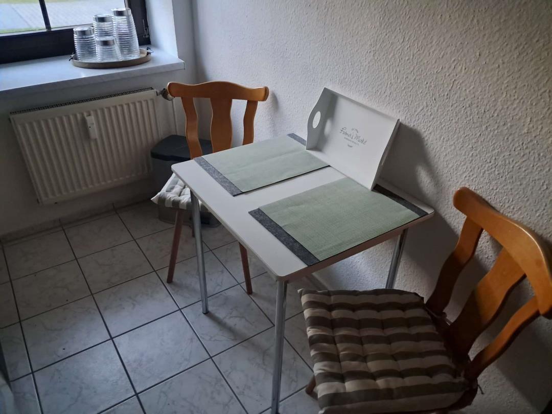 Essplatz mit Tisch, zwei Stühlen und Fenster im Hintergrund.