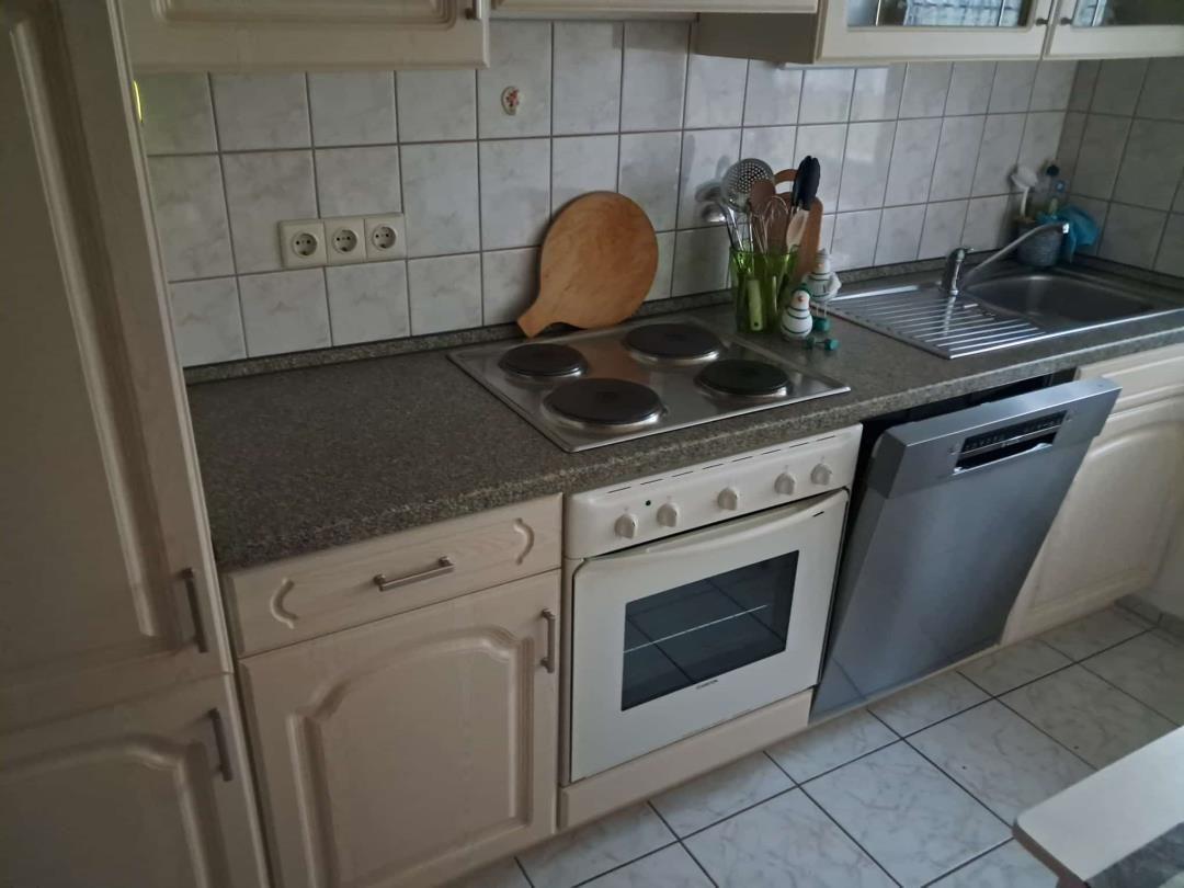 Küche mit Kochfeld, Backofen, Spülmaschine und Arbeitsfläche.