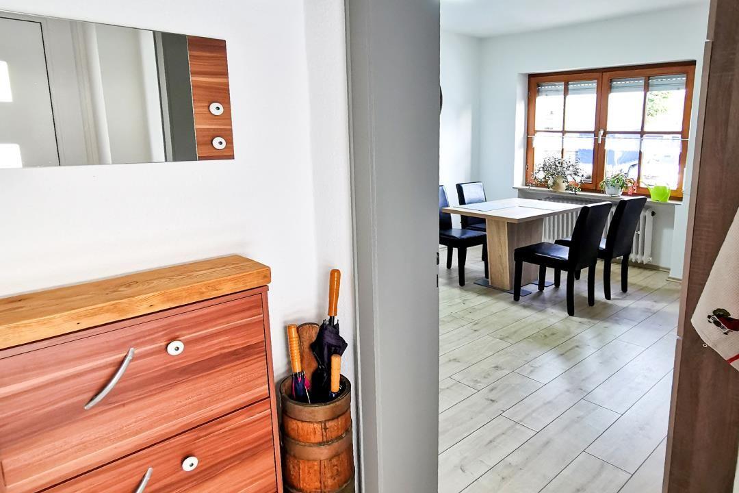 Eingangsbereich mit Schrank und Blick in Esszimmer mit Tisch, Stühlen und Fenster.