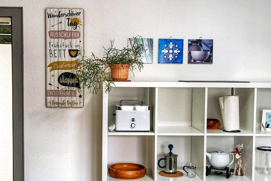 Wand mit Dekoration und Regal mit Küchenutensilien und Pflanze