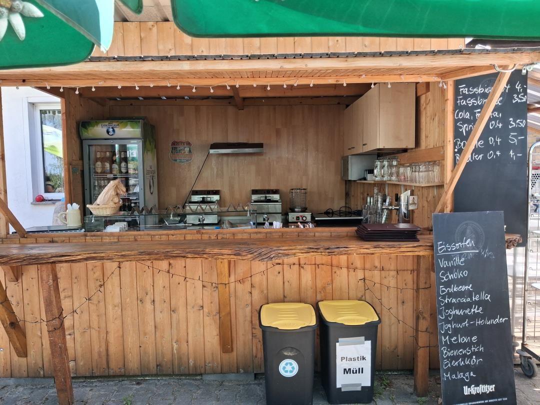 Holzbar mit Getränkeautomat und Menütafel im Freien