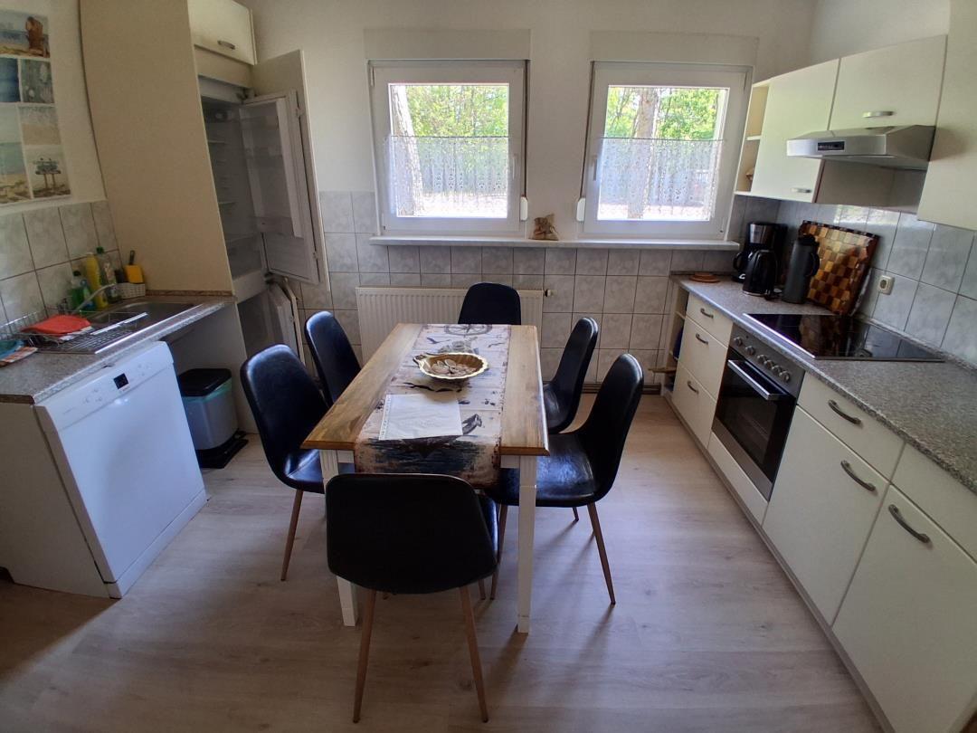 Küche mit Essbereich, Tisch mit sechs Stühlen, Fenster mit Blick auf den Garten.