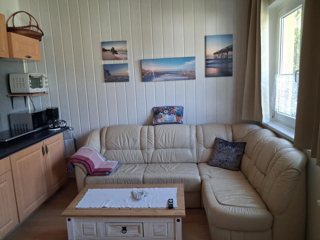 Living room with corner sofa, coffee table, and kitchen area against the wall.