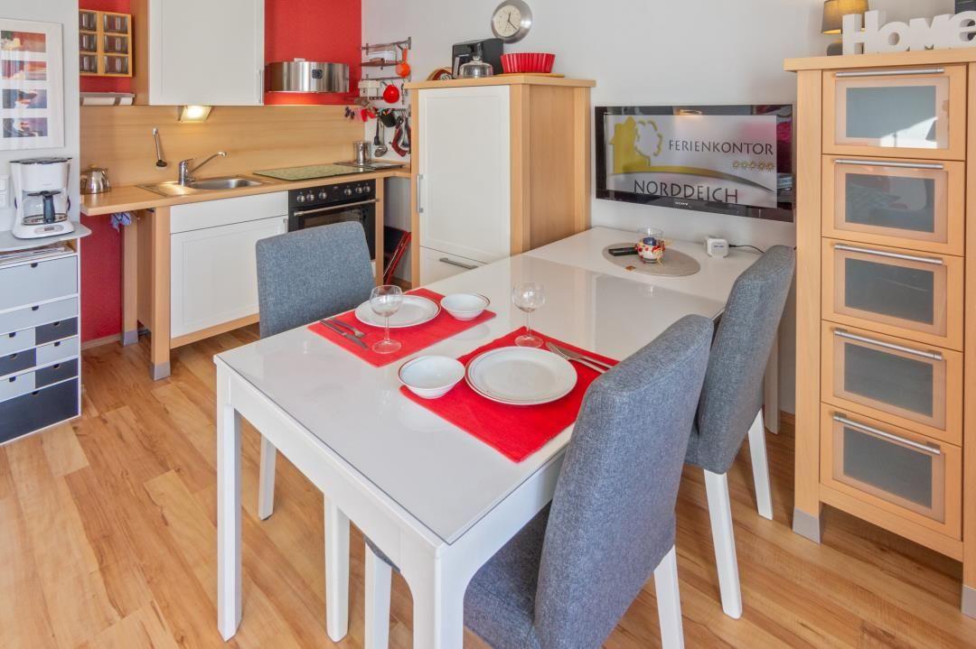 Essbereich mit Tisch, Stühlen und Küchenbereich. Flur mit Schränken und Wanddekoration.