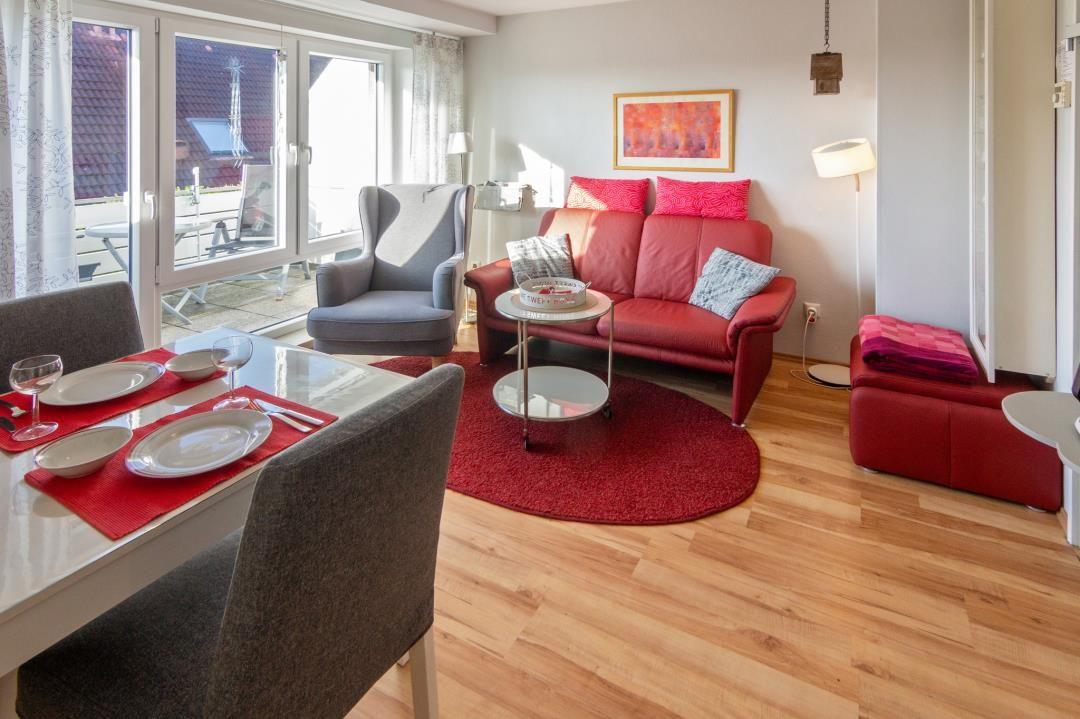 Wohn- und Essbereich mit rotem Sofa, Esstisch und Terrassentür.