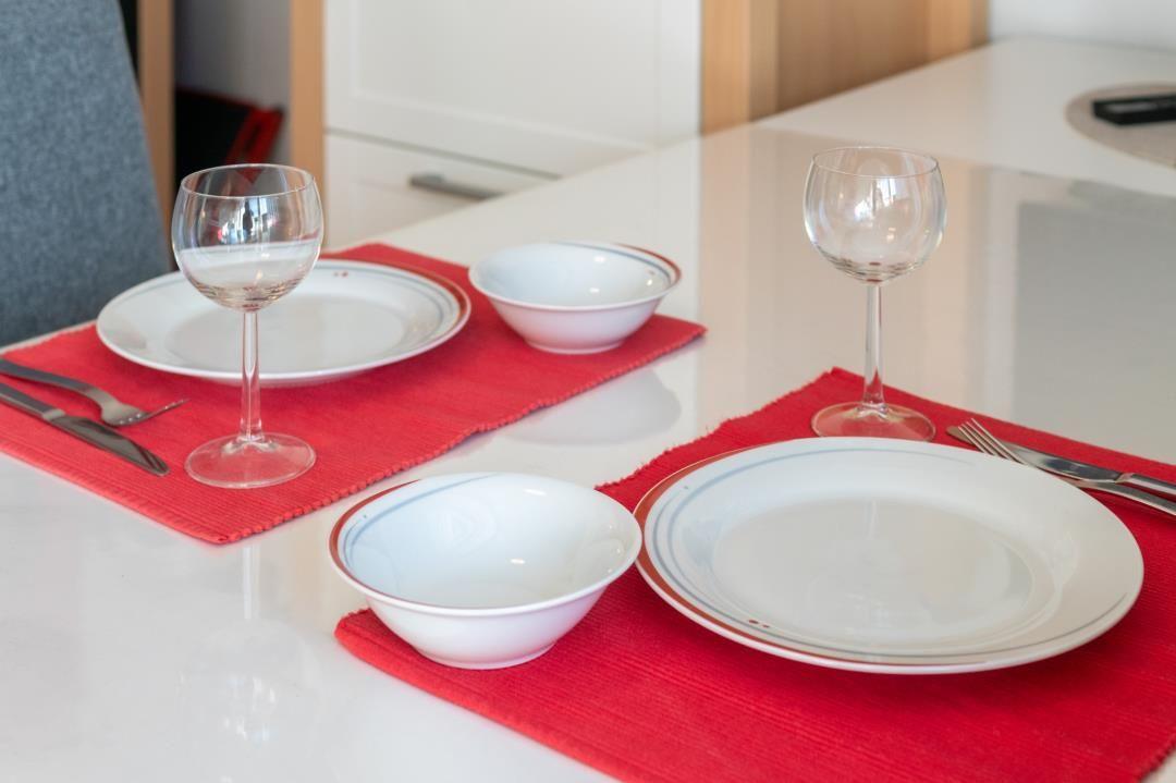Tisch mit zwei Platzsetzungen, roten Untersetzern, weißen Tellern und Gläsern.