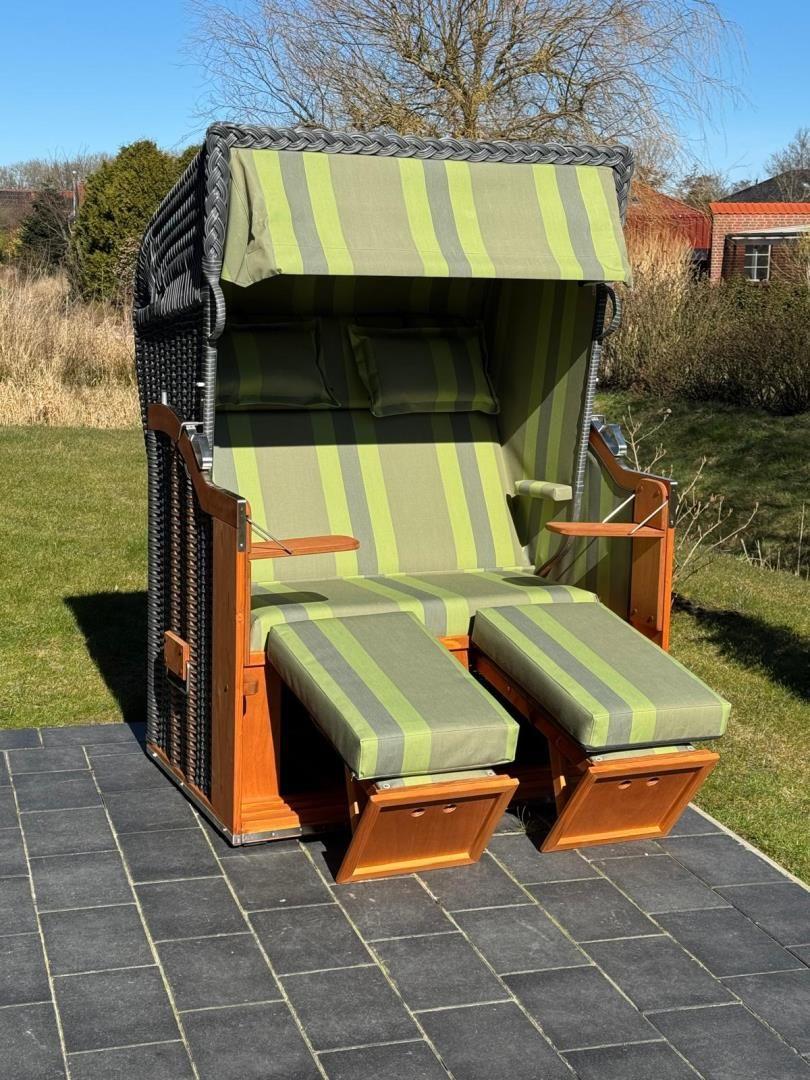 High-quality beach chair with green-white striped fabric and wooden frame on stone tiles.