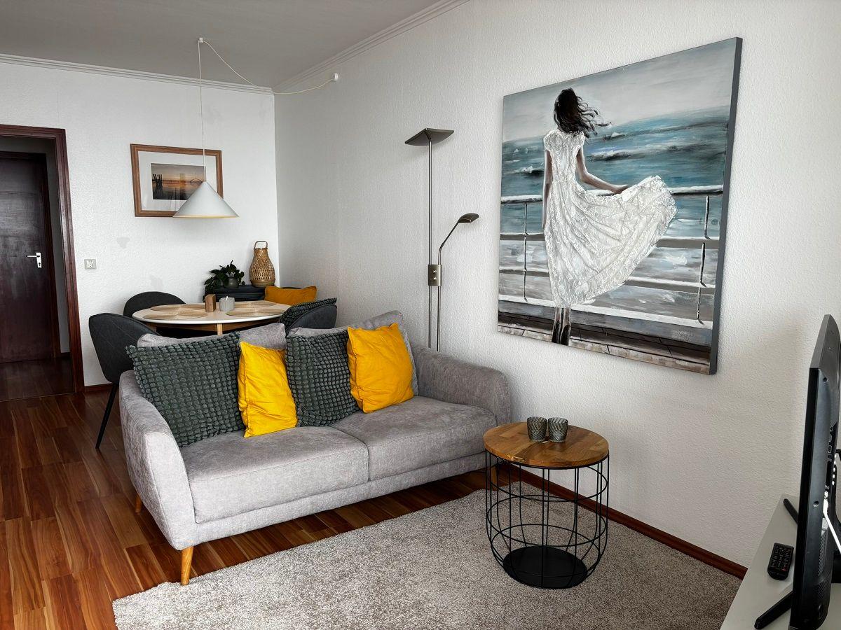 Wohnzimmer mit Sofa, Couchtisch und Wandbild. Holzboden und helle Wände.