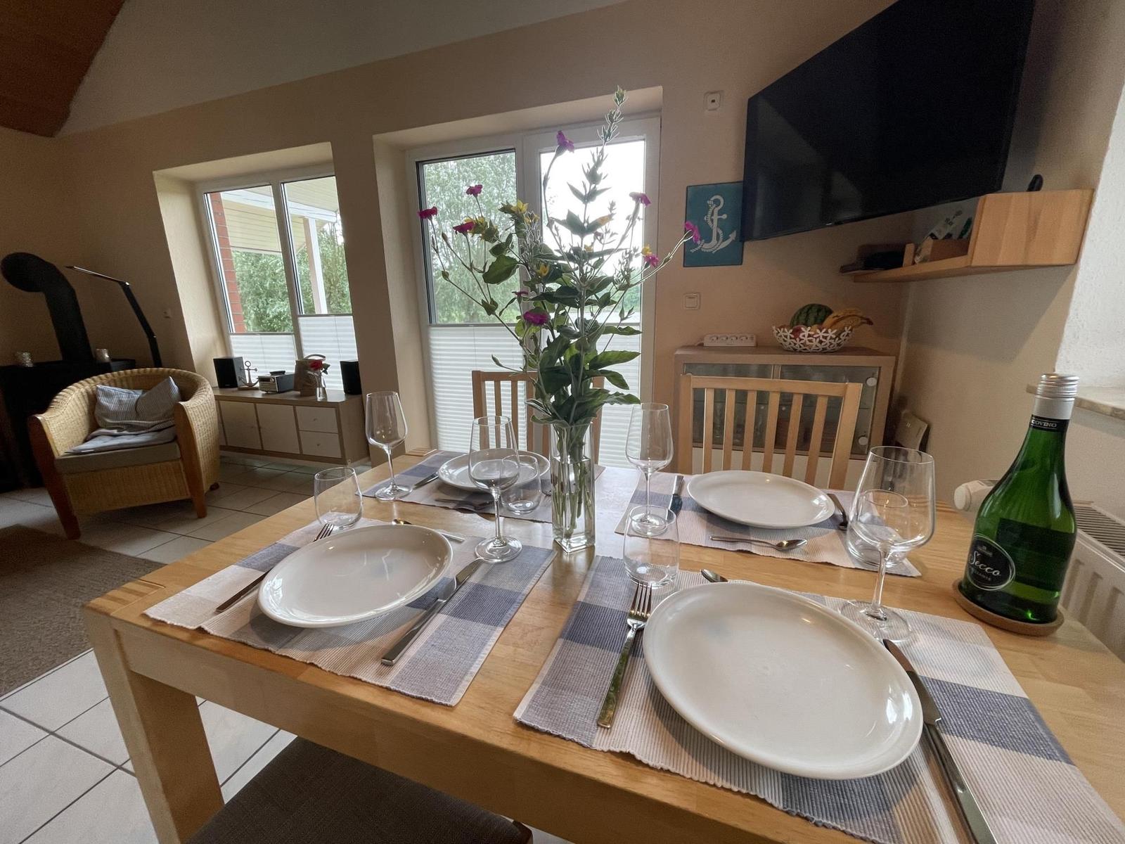 Dining table set for four, flower vase, and TV mounted on the wall.