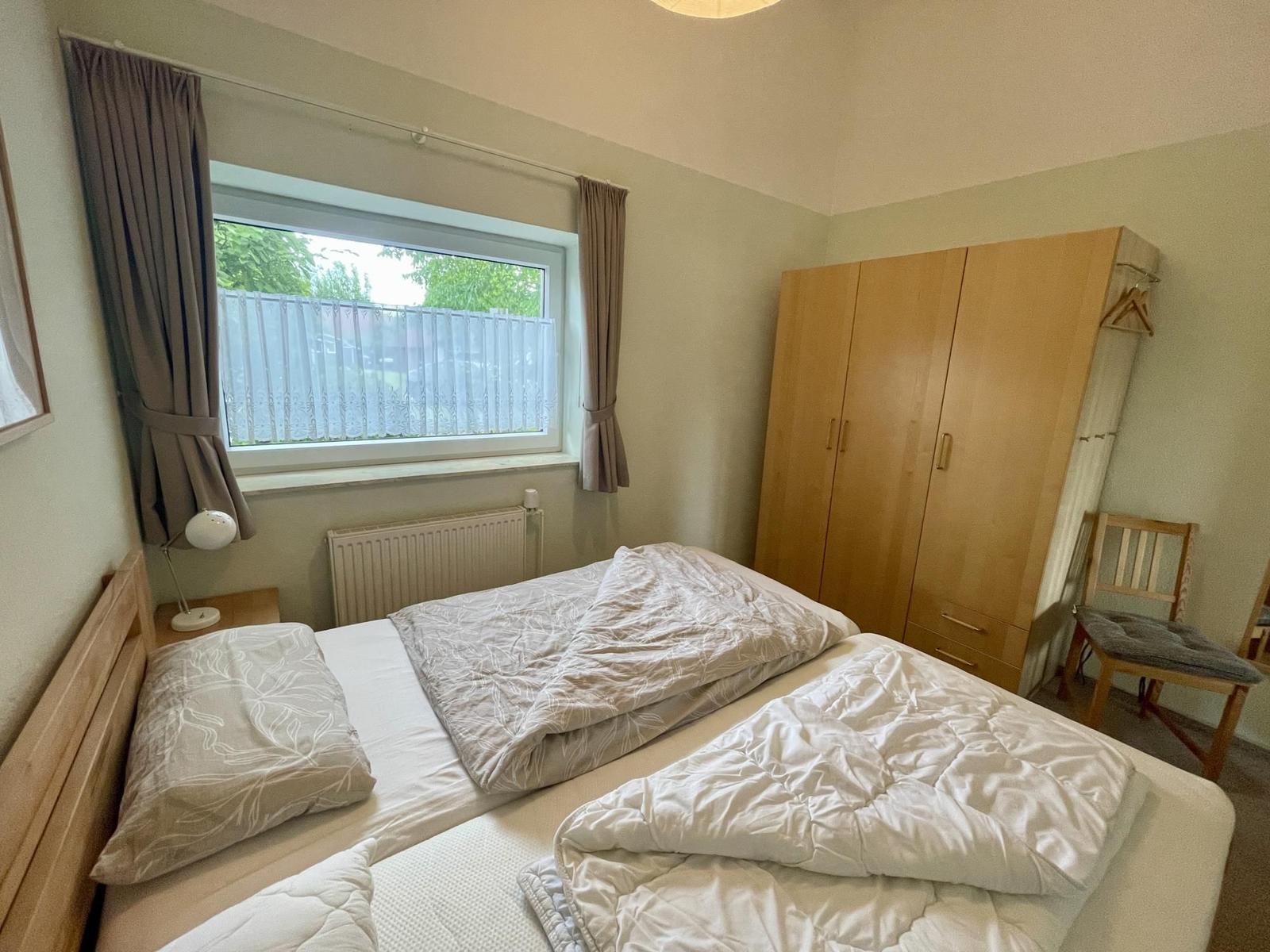 Bedroom with double bed, wardrobe, and window with curtains.