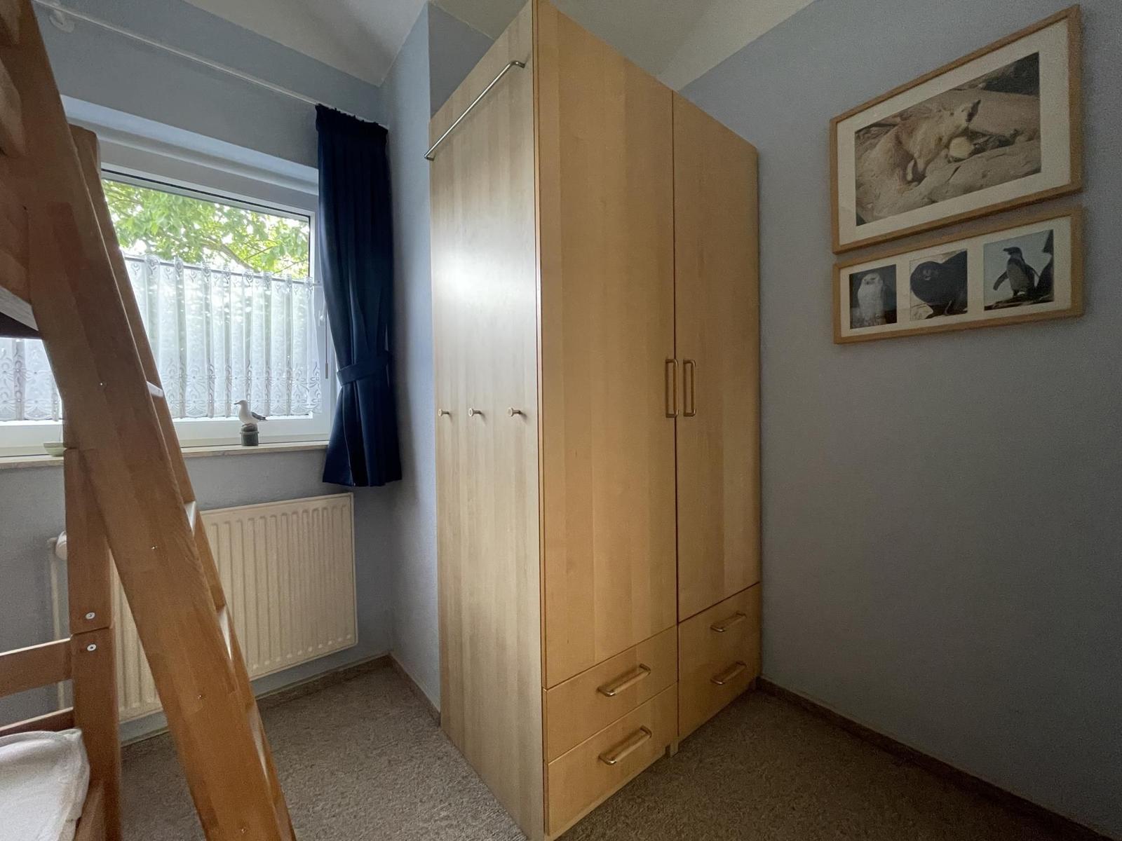 Bedroom with wardrobe, window, and wall pictures