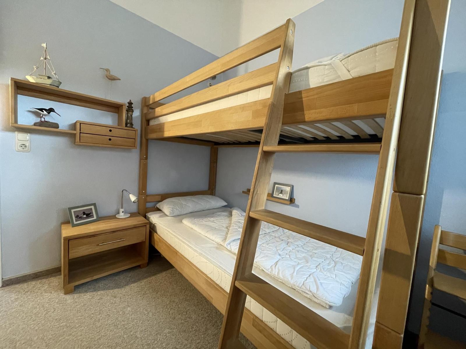 A bedroom with a wooden bunk bed and a nightstand.