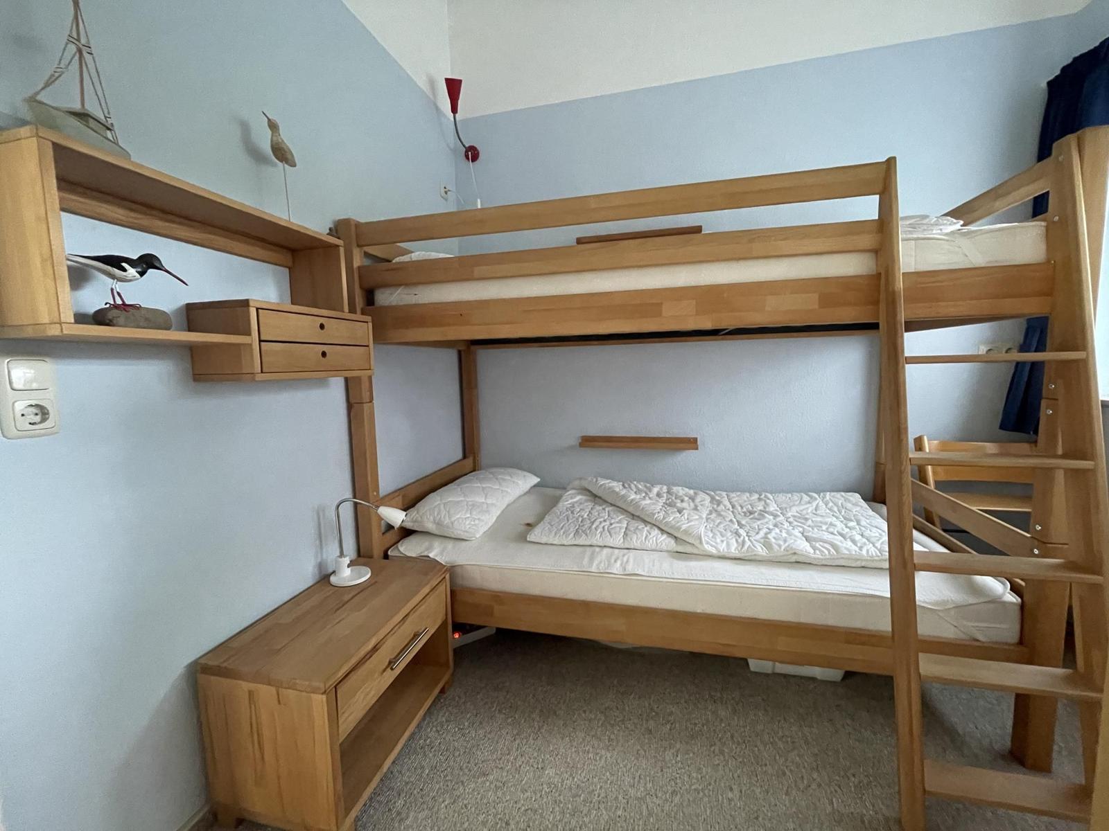 A bedroom with a wooden bunk bed and a bedside table.