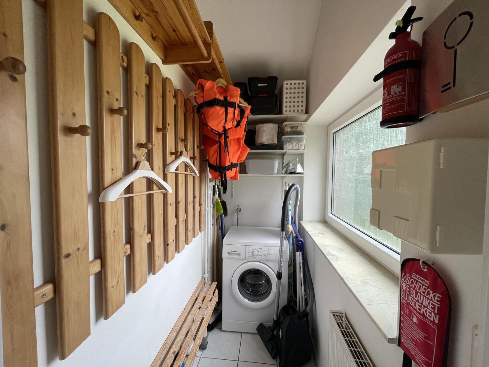 Laundry room with washing machine, coat rack, and window