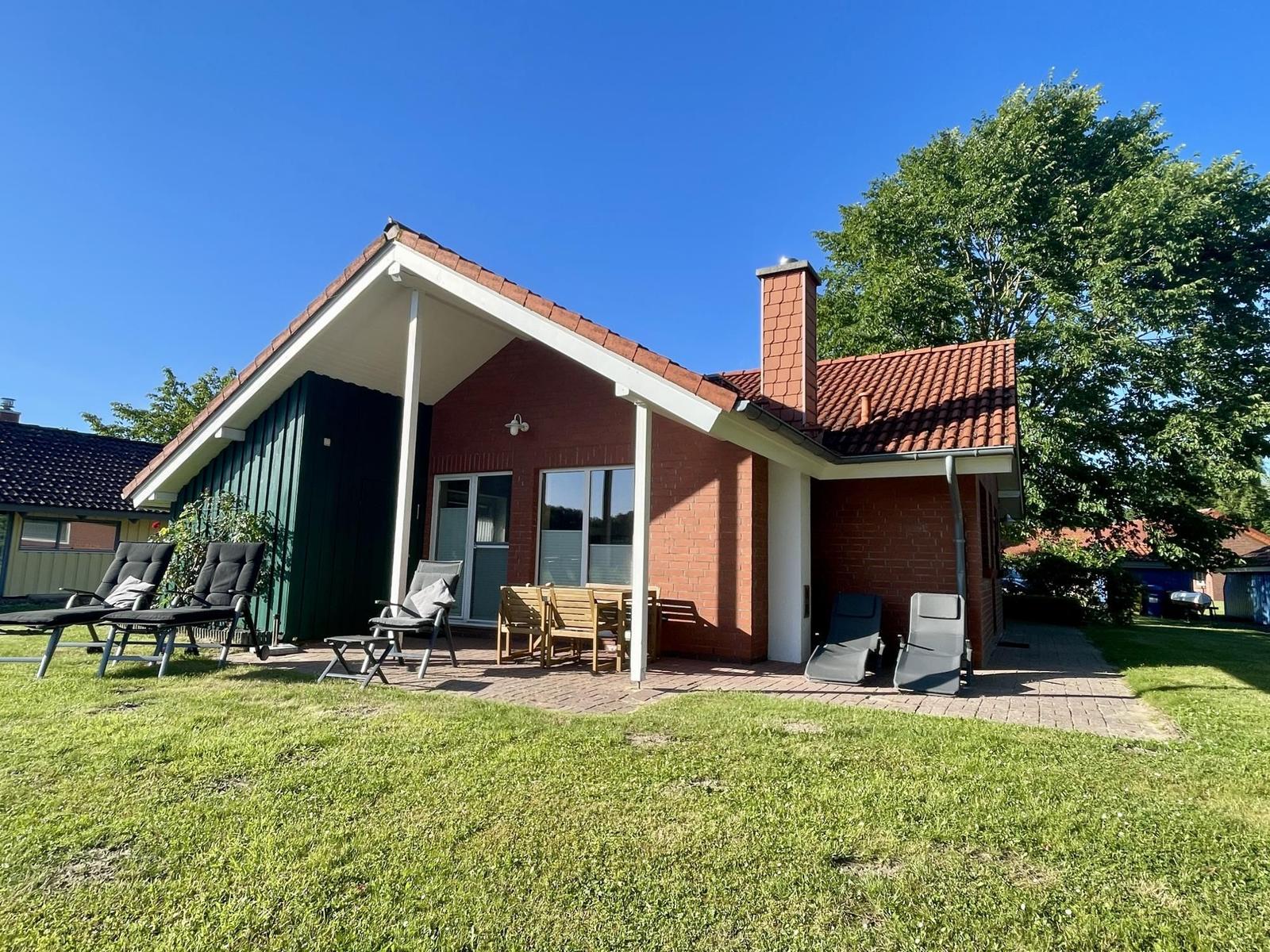 Red brick house with patio and garden. Outdoor seating and barbecue area.