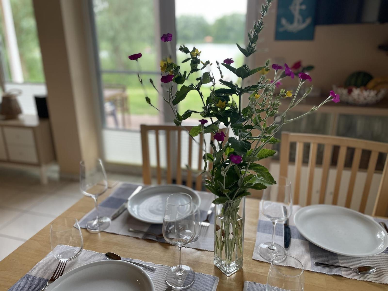 Set dining table with flower vase and view of the lake.