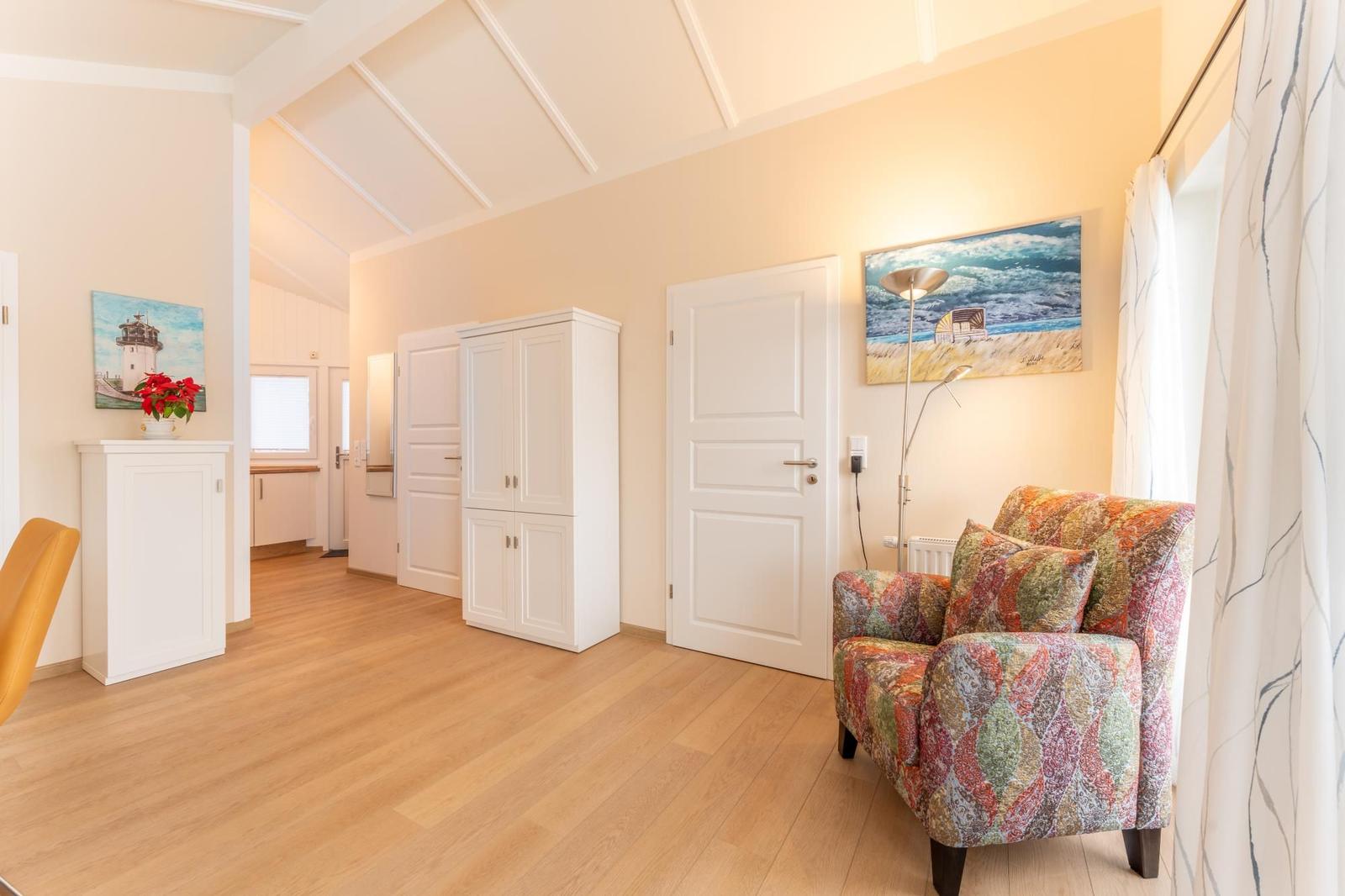 Living area with wooden floor, white doors, and a colorful armchair.