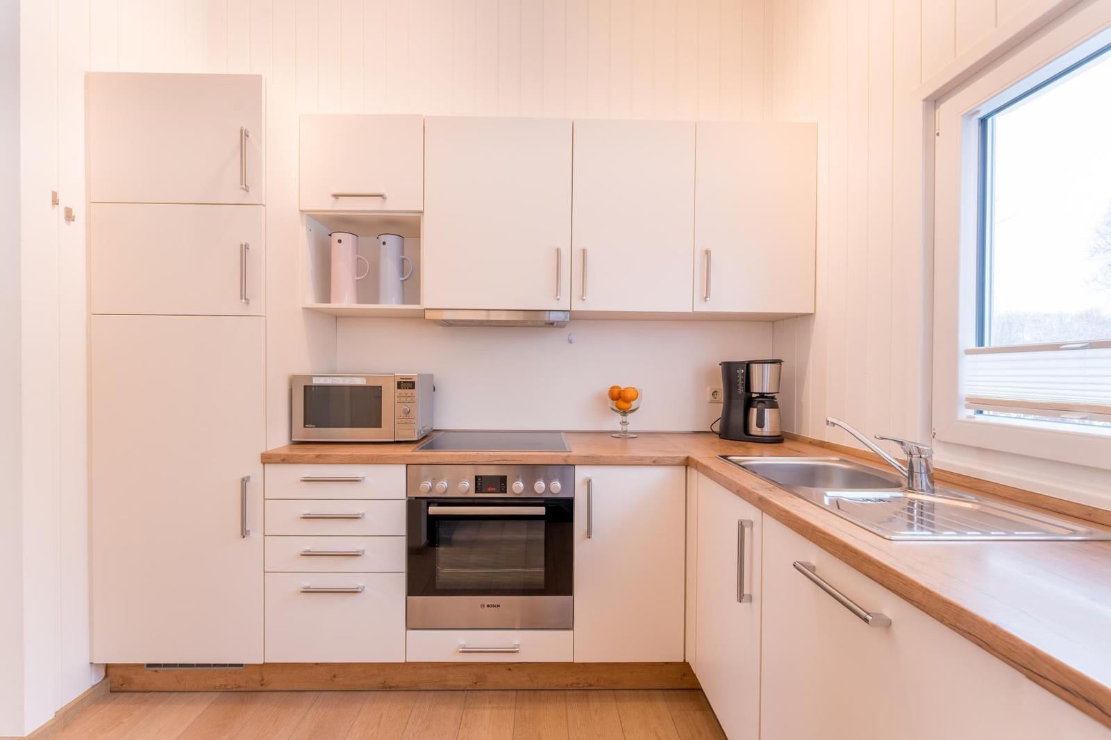 Kitchen with white cabinets, wooden countertop, and built-in stove.