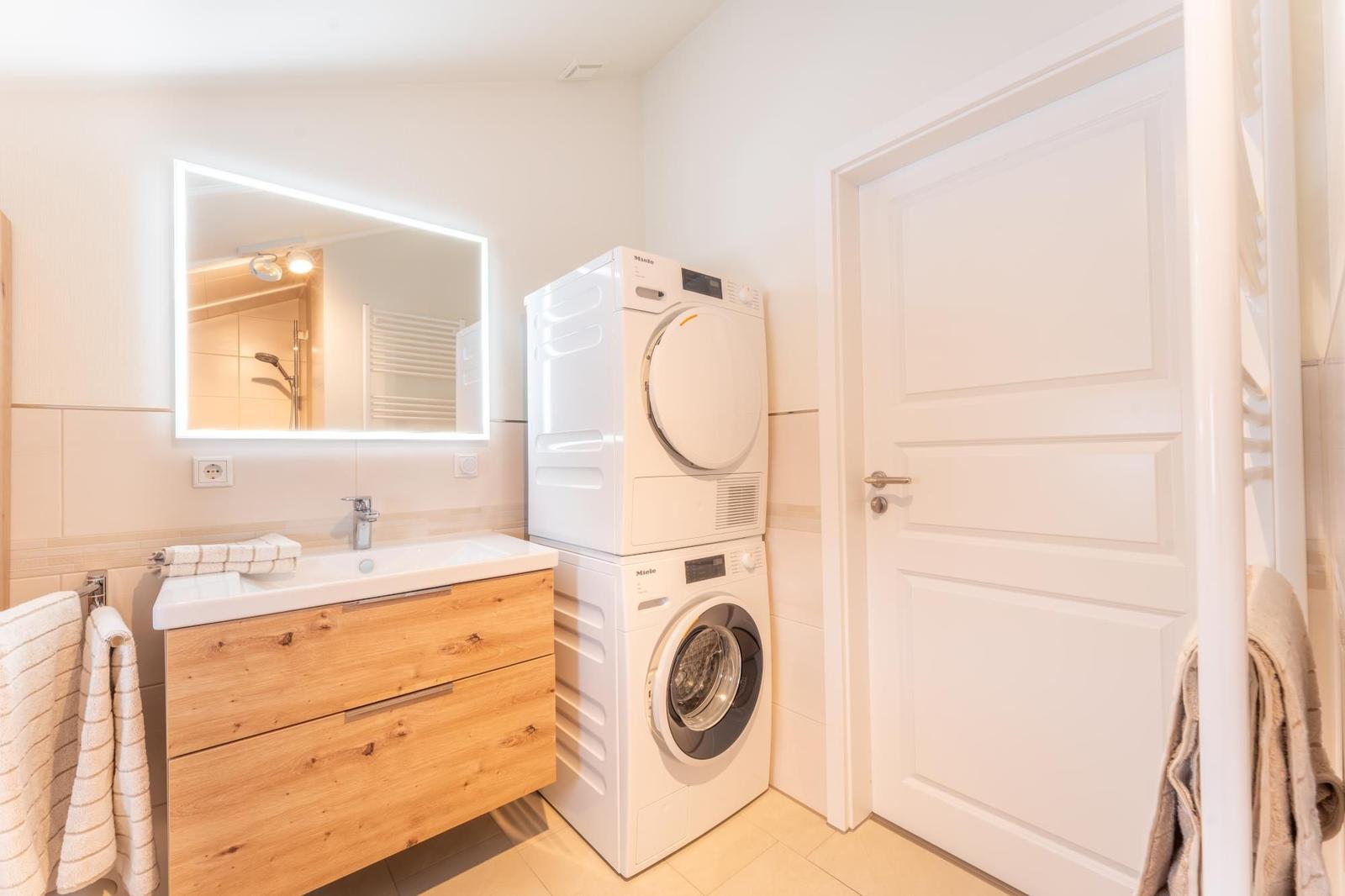 Bathroom with washing machine and dryer, mirror cabinet and towel rack.