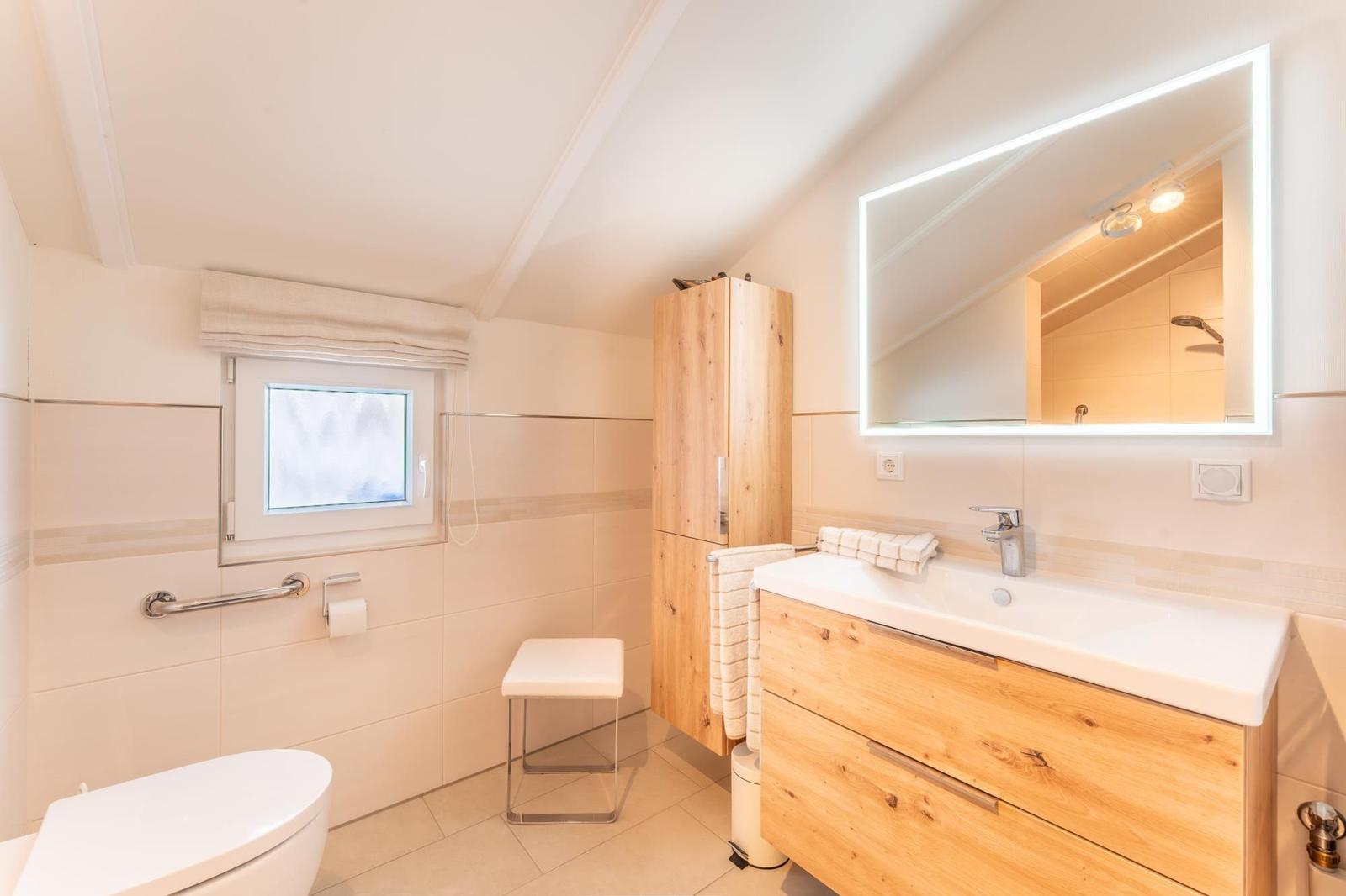 Bathroom with sink, mirror, toilet, and window