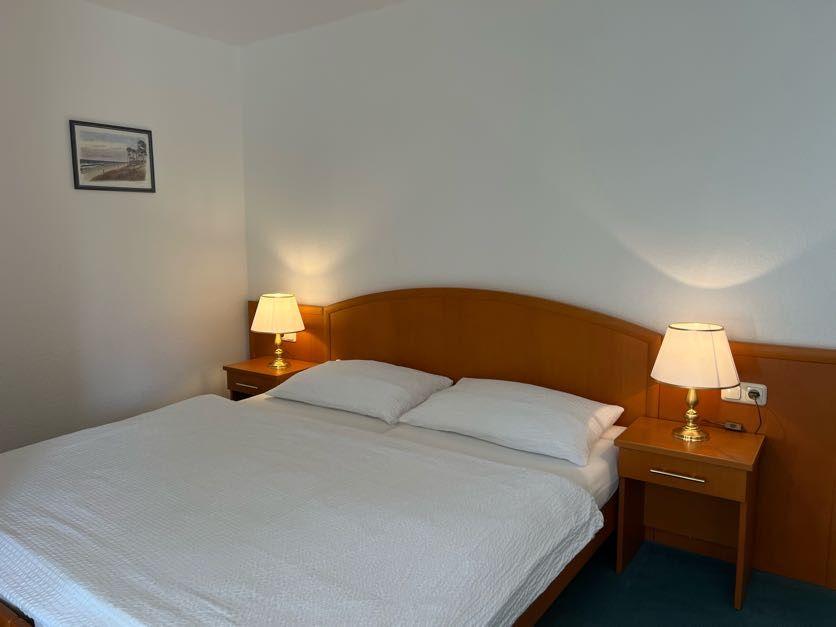 Ein Schlafzimmer mit einem Bett, zwei Nachttischen und Lampen an der Wand.
