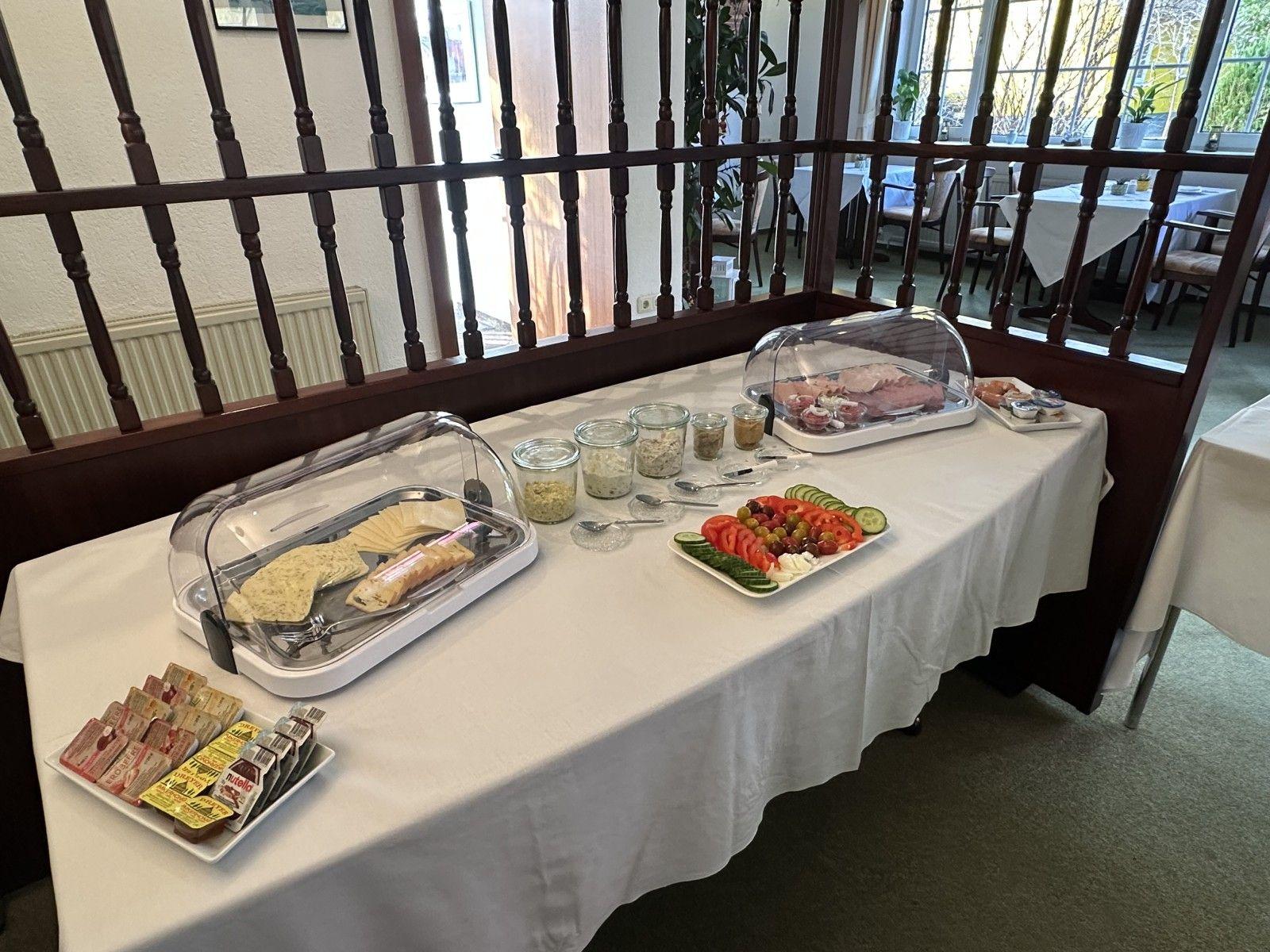 Frühstückstisch mit Käse, Obst, Marmelade und Getränken.