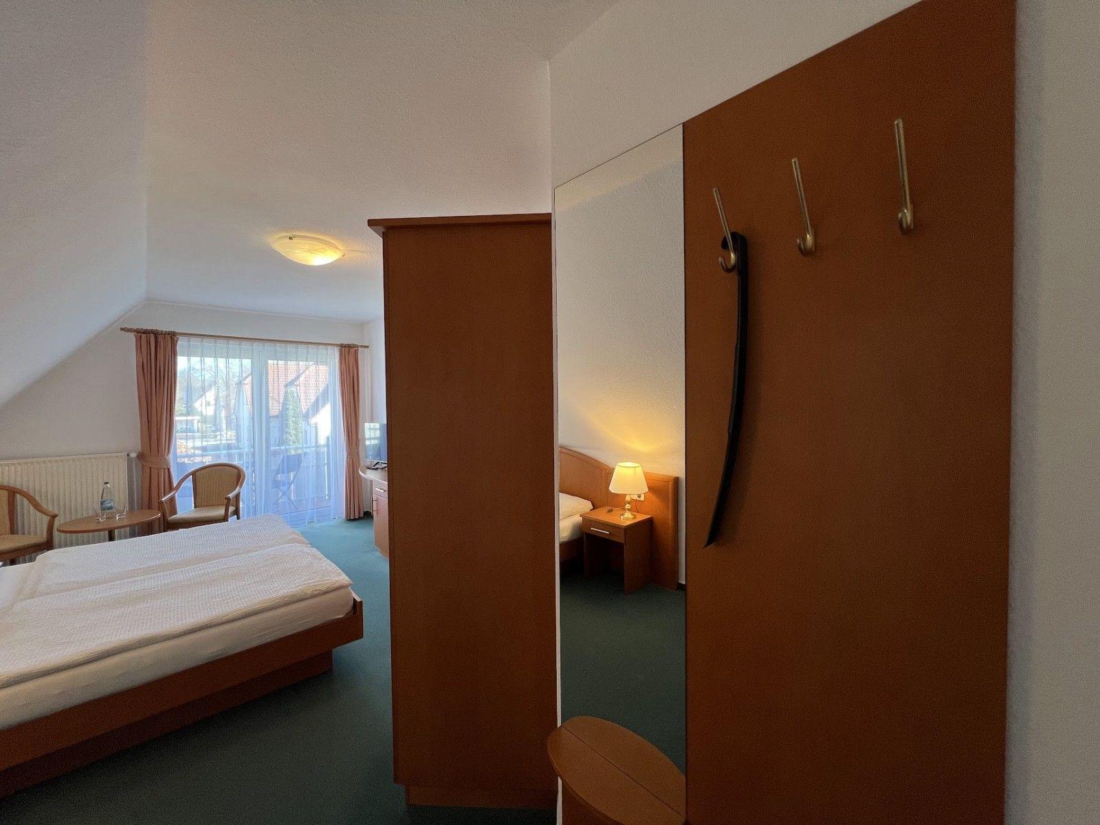 Schlafzimmer mit Bett, Kleiderschrank und Blick auf Balkon.
