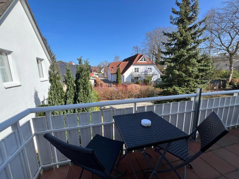Terrasse mit Tisch und Stühlen, Blick auf Haus und Bäume.