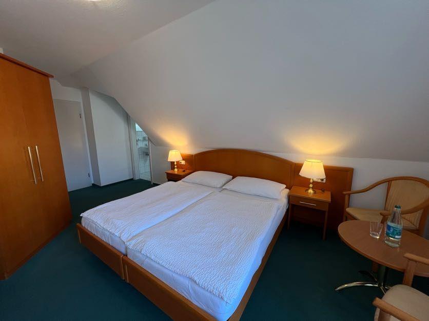 Schlafzimmer mit Doppelbett, Nachttischen und Schrank unter schräger Decke.