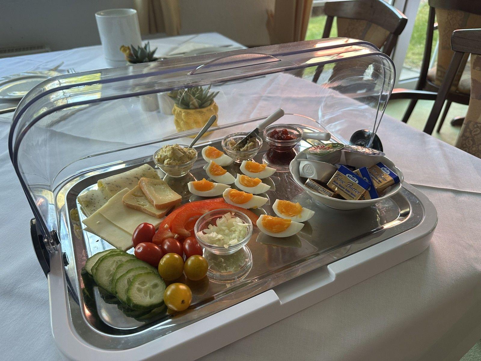 Frühstückstablett mit Käse, Eiern, Gemüse und Butter