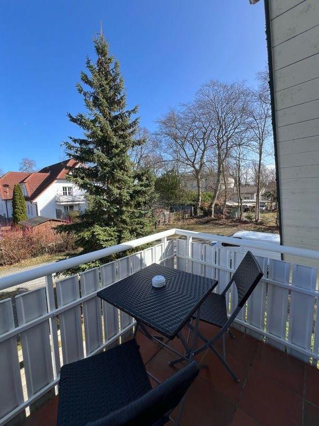Terrasse mit Tisch und Stühlen. Blick auf Baum und Nachbarhaus.