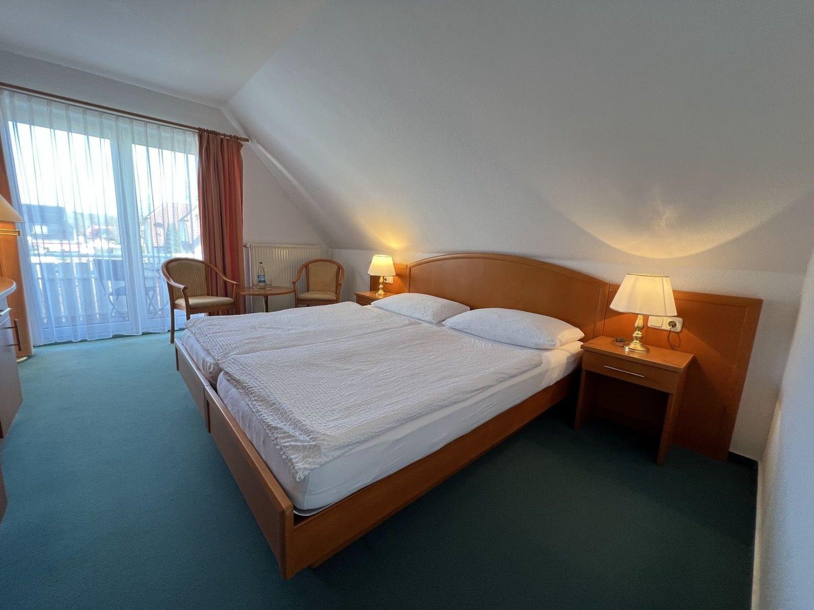 Ein Schlafzimmer mit Doppelbett, zwei Nachttischen und einem Balkon.