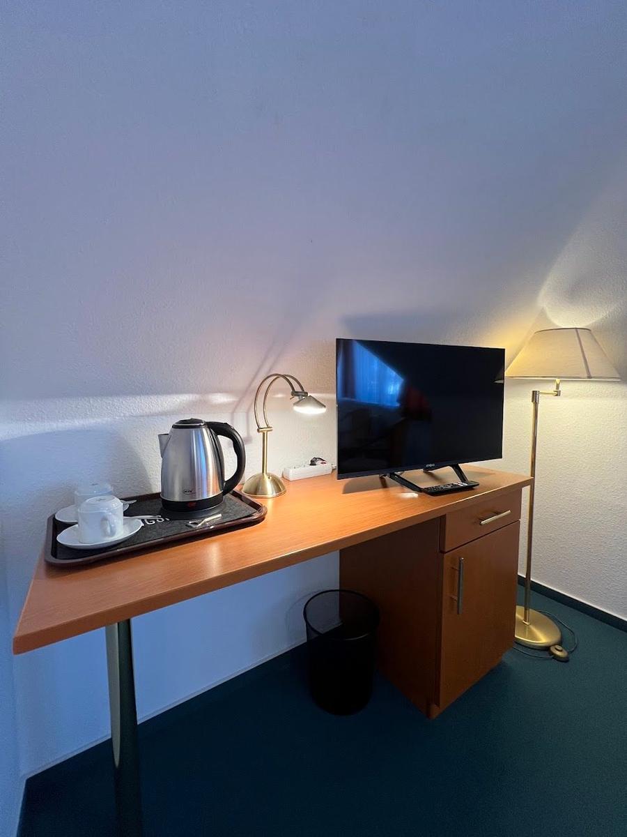 Schreibtisch mit Fernseher, Kaffeemaschine und Stehlampe.