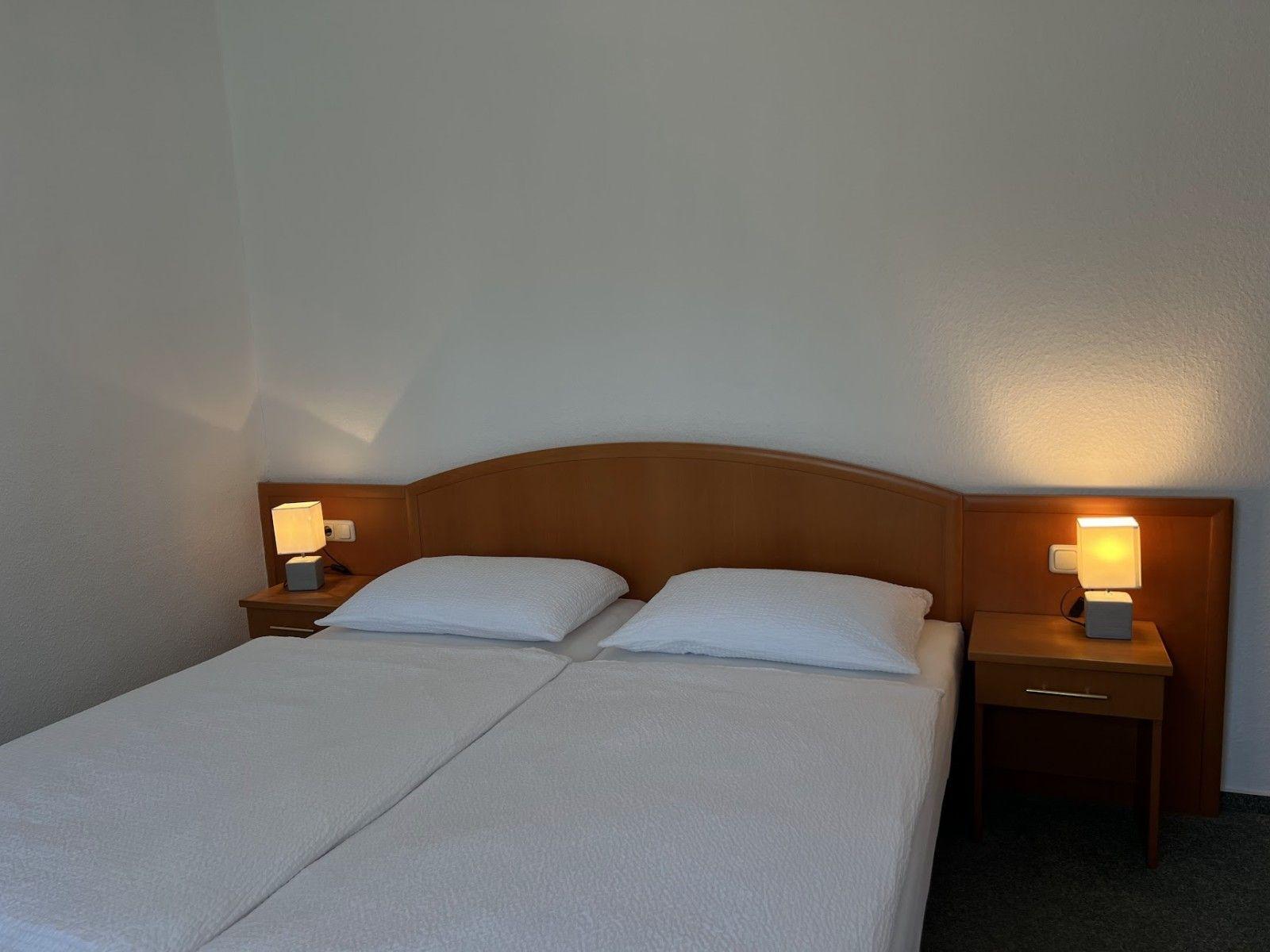 Doppelbett mit zwei Nachttischen und Lampen an der Wand