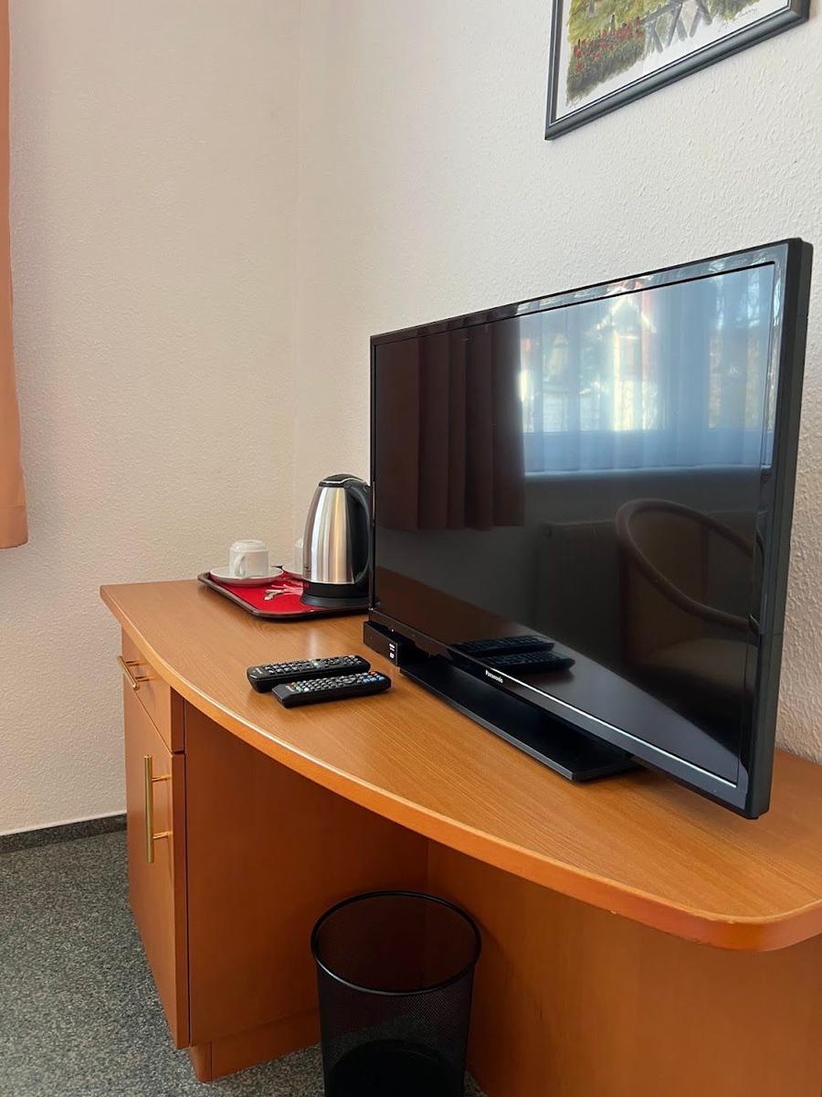 Schreibtisch mit Fernseher, Kaffeemaschine und Fernbedienungen.