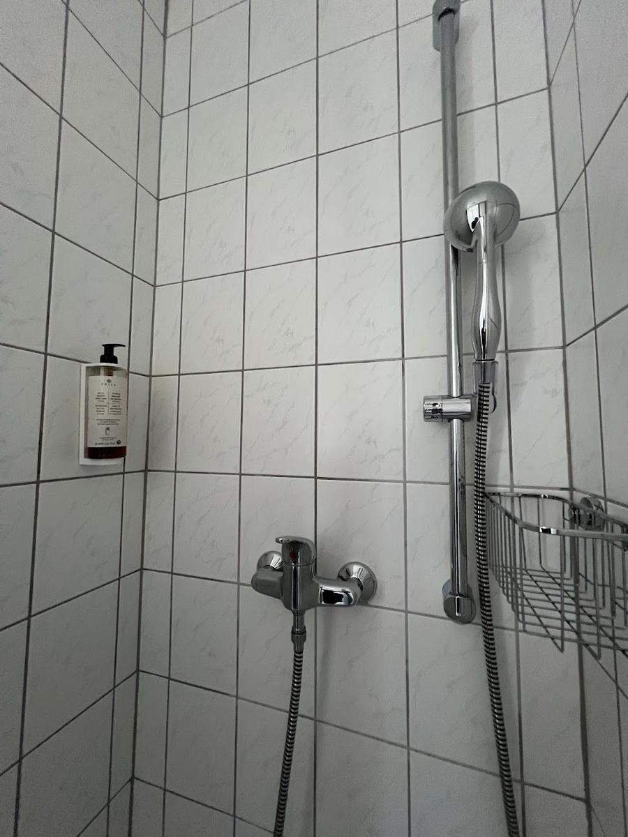 Dusche mit Duschbrause, Handbrause und Seifenspender an Wand