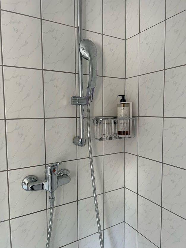 Dusche mit Duschbrause, Duschstange und Duschgelhalterung.