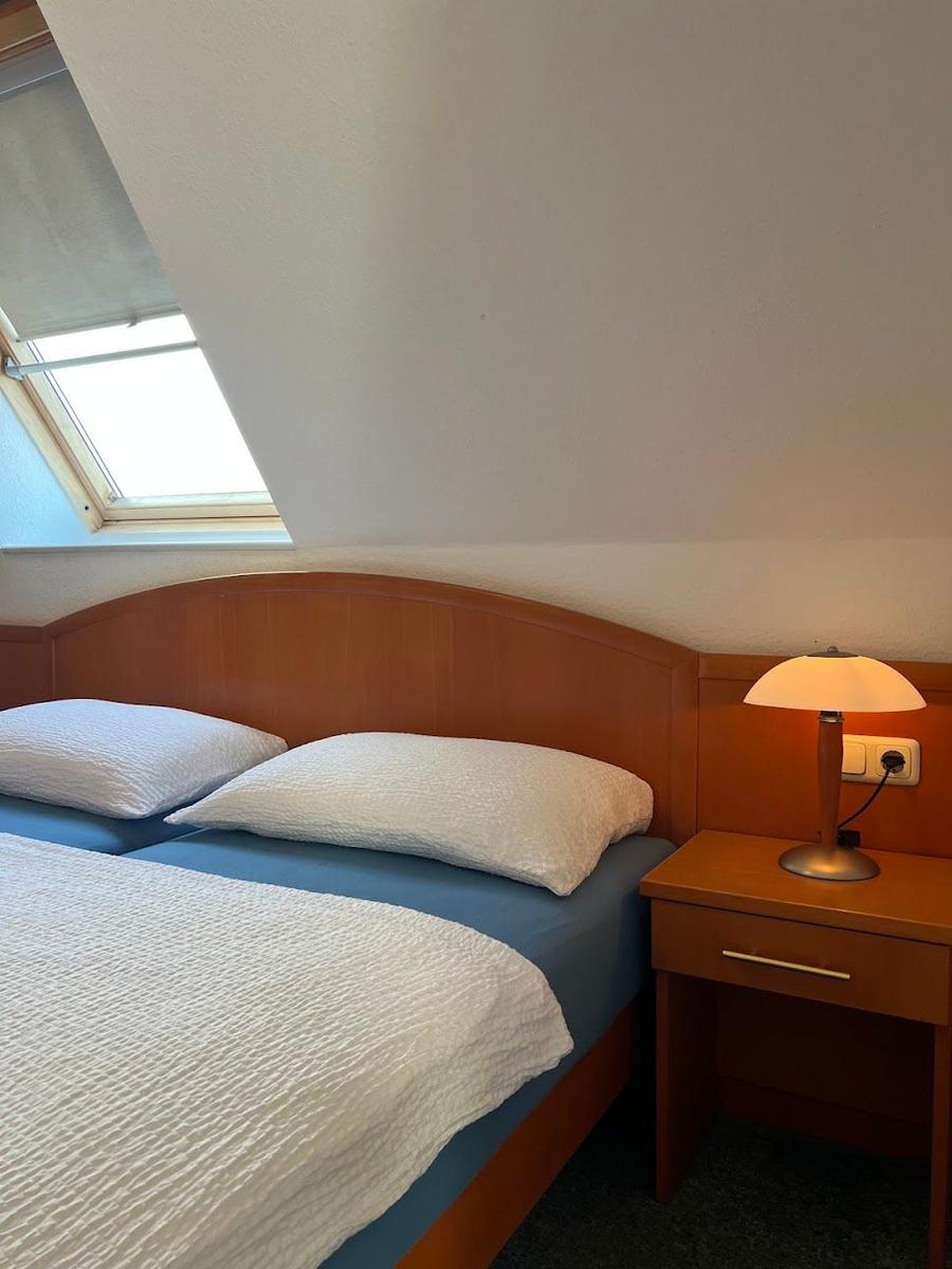 Schlafzimmer mit Doppelbett, Nachttisch und Dachfenster.