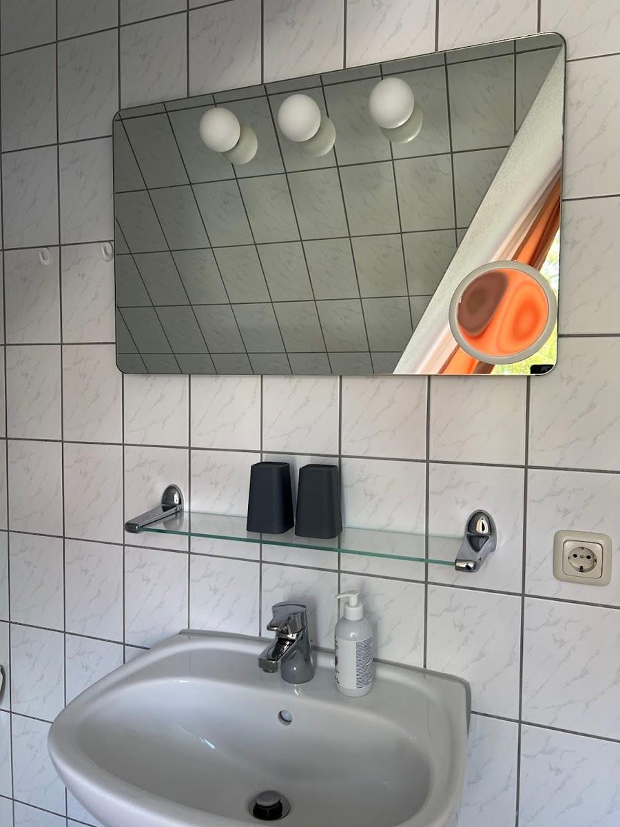Badezimmer mit Waschbecken, Spiegel und Duschbrause