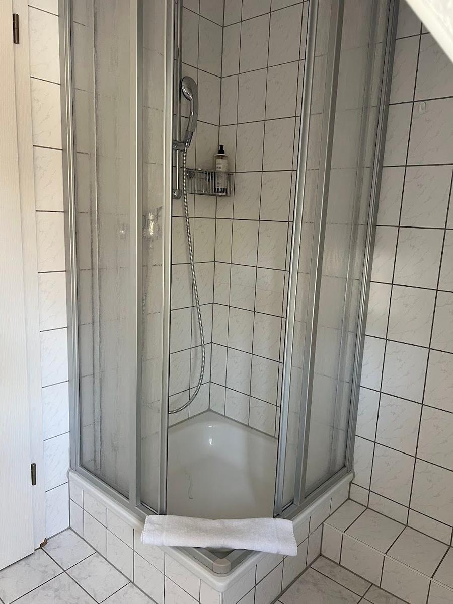 Duschkabine mit Duschbrause und Handtuch auf dem Rand