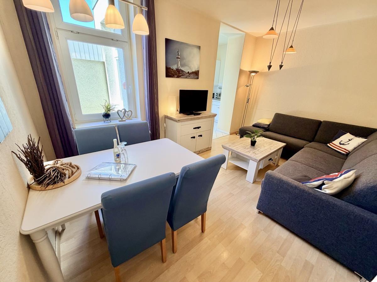 Wohn- und Essbereich mit Sofa, Esstisch und Fenster. Wandbild und TV sichtbar.