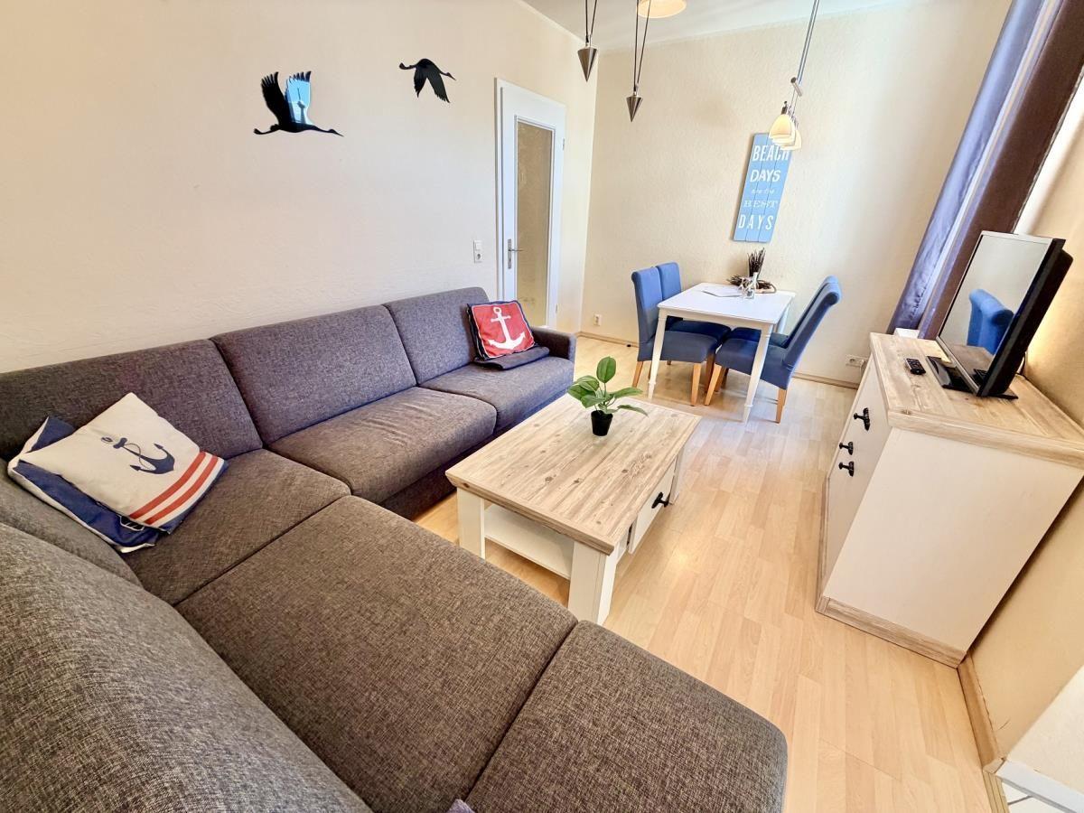 Wohnzimmer mit Sofa, Couchtisch und Essbereich mit Tisch und Stühlen.