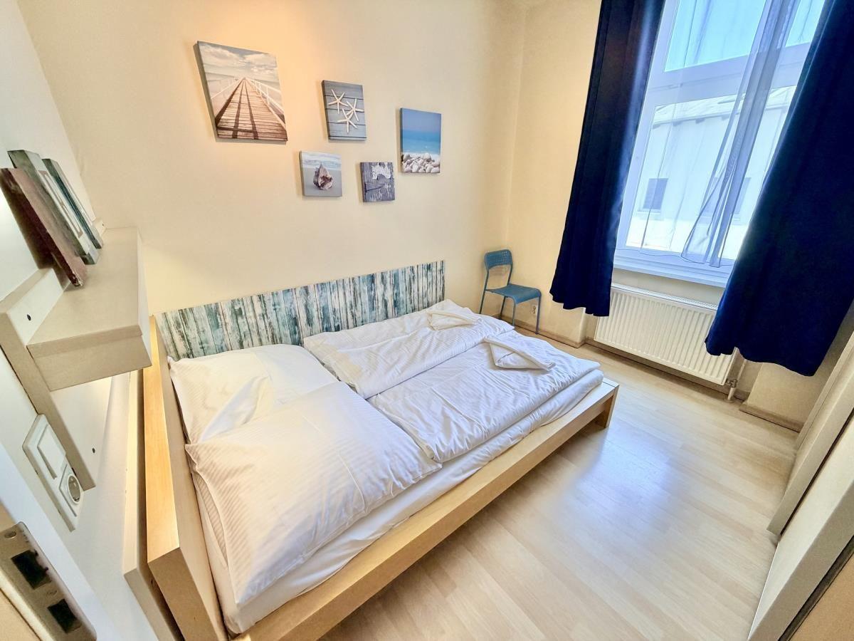 Schlafzimmer mit Bett, Wandbildern und Fenster mit Vorhängen.