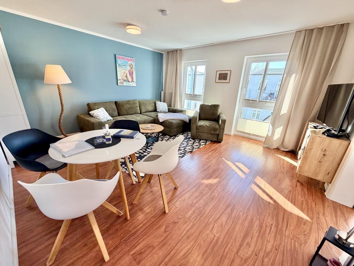 Wohnzimmer mit Sofa, Essplatz und Blick auf Balkon.