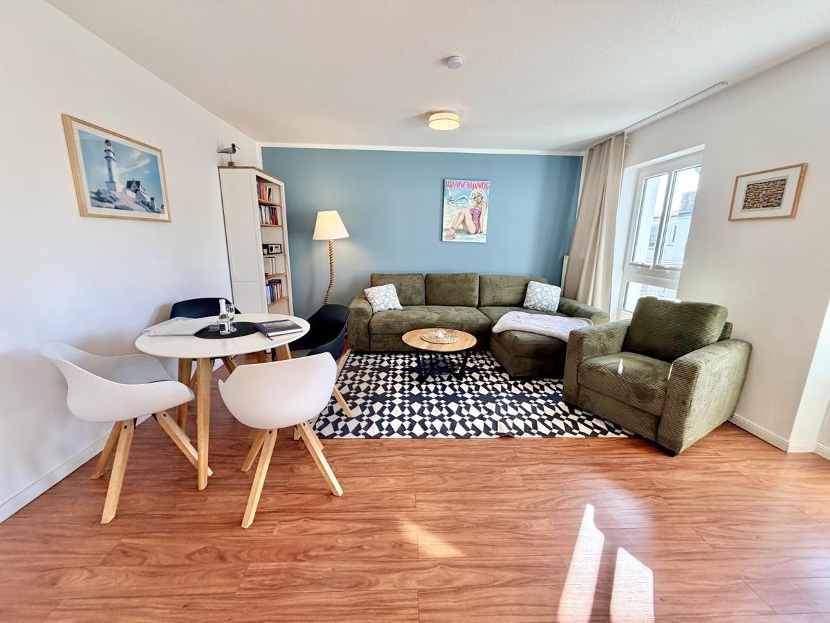 Wohnzimmer mit Sofa, Sessel, Tisch und Stühlen auf Holzboden.
